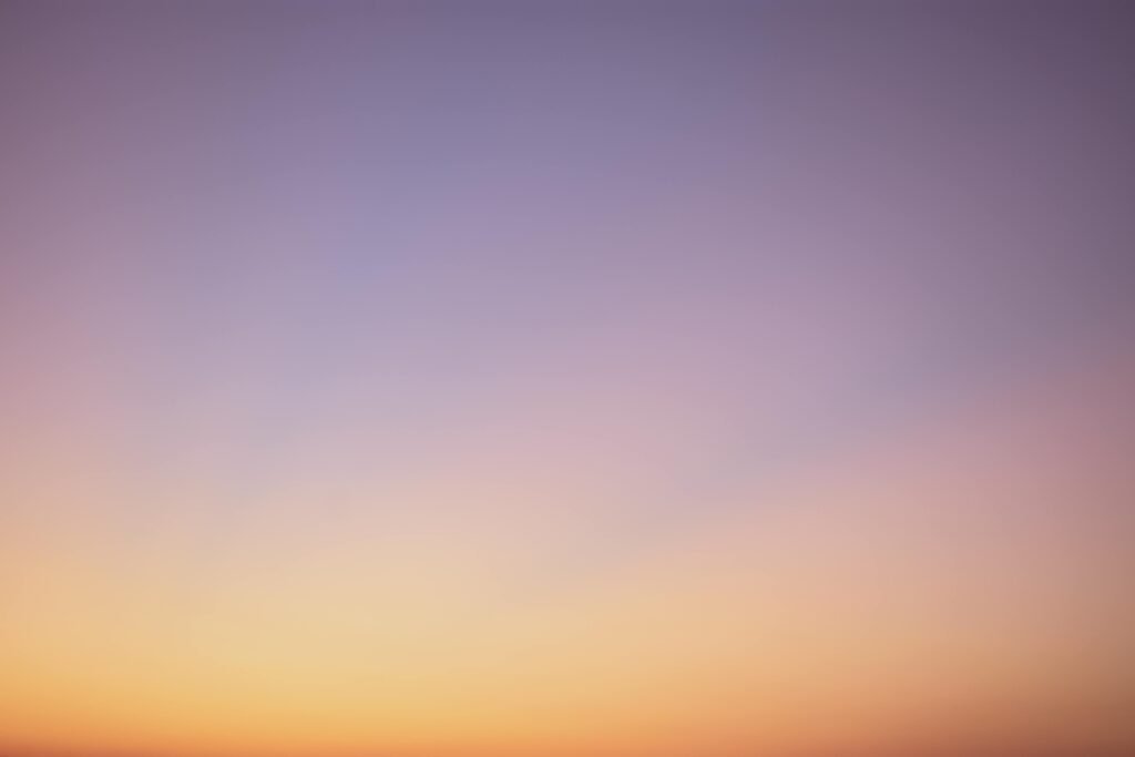 A serene gradient sky with hues of blue, pink, and orange during twilight.